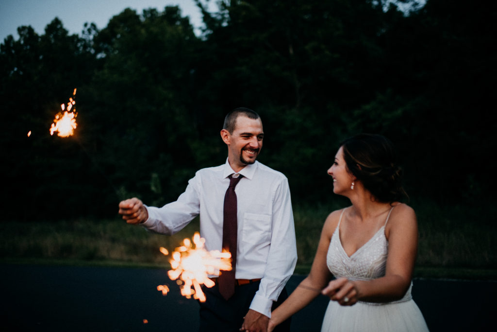 bride and groom holding sparklers and smiling at each other