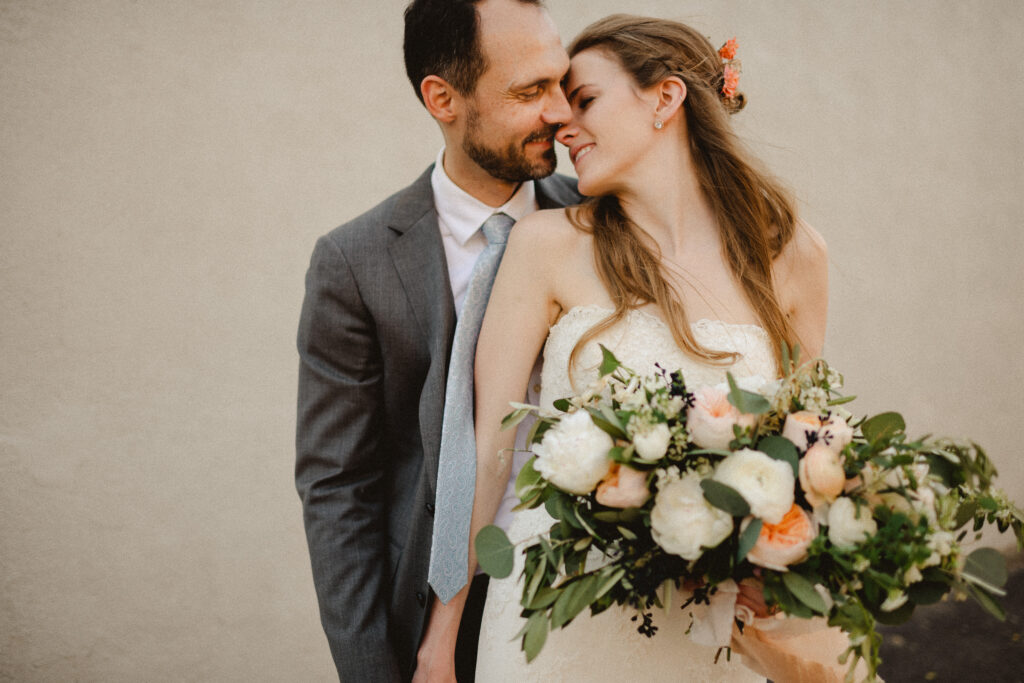 A groom stands behind his bride, snuggling into her neck after their Palm Springs elopement wedding