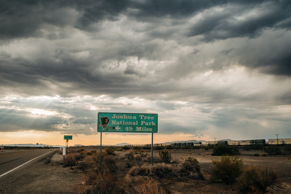 image of a worn sign that reads "Joshua Tree National Park 49 Miles"
